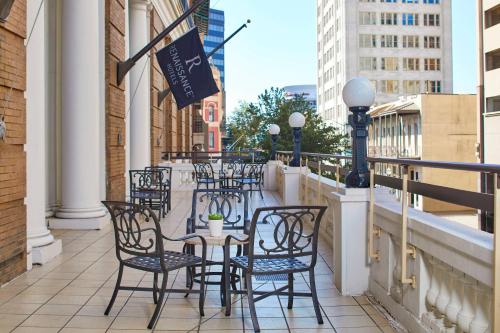 a patio with tables and chairs on a balcony at The Battle House Renaissance Mobile Hotel & Spa in Mobile