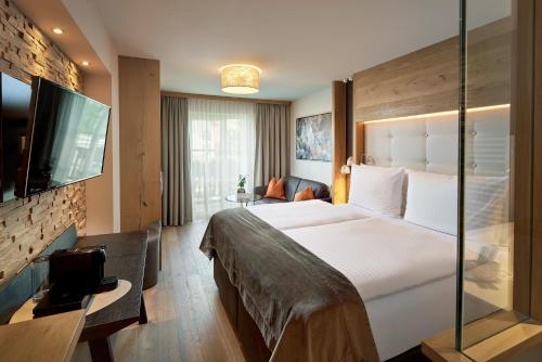 a hotel room with a large bed and a television at Wellness- & Sporthotel Jagdhof in Röhrnbach