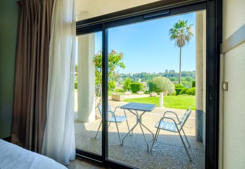 - une chambre avec vue sur une terrasse dotée d'une table et de chaises dans l'établissement B&B HOTEL Villeneuve Loubet Village, à Villeneuve-Loubet
