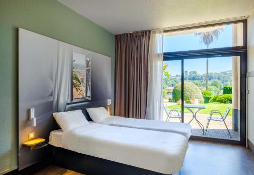 une chambre d'hôtel avec un lit et une grande fenêtre dans l'établissement B&B HOTEL Villeneuve Loubet Village, à Villeneuve-Loubet