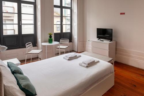 a bedroom with a bed with two chairs and a television at Citybreak-apartments Lapa in Porto