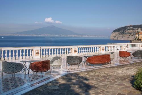 a group of chairs and a table on a balcony overlooking the water at Parco dei Principi in Sorrento