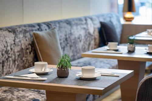 due tavoli in un ristorante con tazze da caffè e una pianta di AC Hotel A Coruña by Marriott a La Coruña