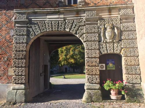 une arche en pierre avec une porte et une plante dans l'établissement Château de Romécourt, à Tarquimpol