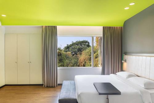 sala de estar con sofá blanco y ventana en Park Inn by Radisson,South Delhi, en Nueva Delhi