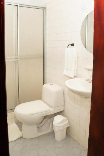 a white bathroom with a toilet and a sink at Hotel Boulevard del Río in Cali