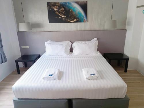 Un dormitorio con una cama blanca con dos toallas encima. en Whale Hostel Cha-Am, en Cha Am