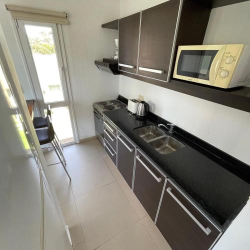 una cucina con piano di lavoro nero e forno a microonde di NovaVista Apart & Spa a Villa Gesell