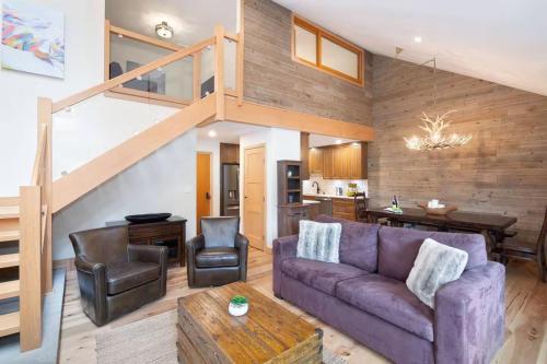 a living room with a purple couch and a staircase at Large Village loft with Private Hot Tub and Private Sauna in Whistler