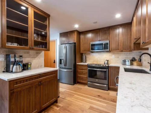 a kitchen with wooden cabinets and stainless steel appliances at Large Village loft with Private Hot Tub and Private Sauna in Whistler