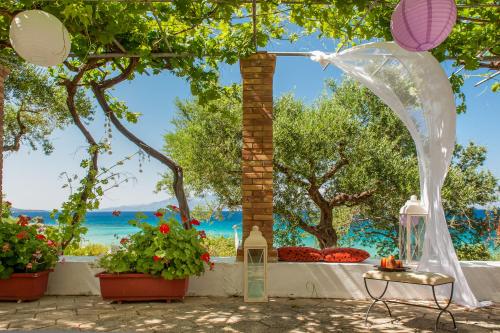 an arch with flowers and a view of the ocean at Ammos Apartments in Alikanas