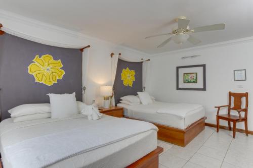 a bedroom with two beds and a ceiling fan at Villa Boscardi in Belize City