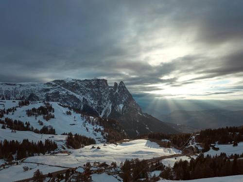 a snow covered mountain with the sun shining on it at COMO Alpina Dolomites in Alpe di Siusi