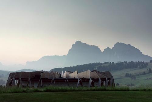 an old building in a field with mountains in the background at COMO Alpina Dolomites in Alpe di Siusi