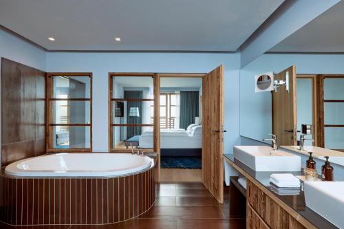 a bathroom with a large tub and a bedroom at COMO Alpina Dolomites in Alpe di Siusi