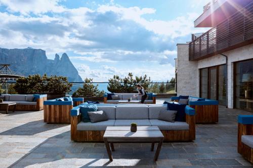 a patio with couches and a view of the mountains at COMO Alpina Dolomites in Alpe di Siusi