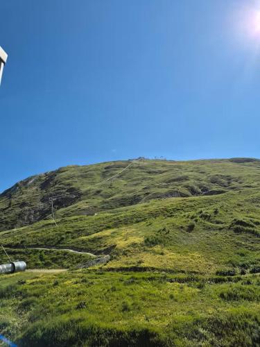 une colline avec de l'herbe verte et un ciel bleu dans l'établissement HB 1613 - Beau T2, 5pers, ski aux pieds, à Tignes
