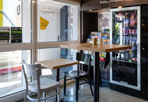 a restaurant with a table and chairs and a refrigerator at B&B HOTEL Grenoble Université 1 in Gières