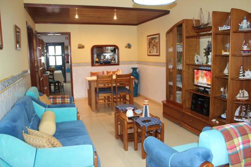 a living room with blue couches and a dining room at Ti Laura Praia in Praia da Barra