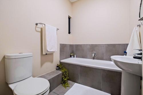 a bathroom with a toilet and a tub and a sink at Ridge Comfort in Midrand