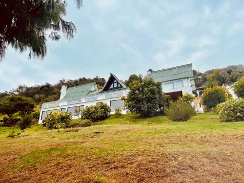 a white house on top of a grassy hill at El Silencio del Sisga in Chocontá