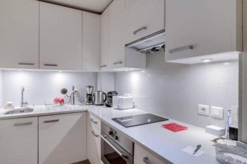 une cuisine blanche avec des armoires blanches et un évier dans l'établissement The Triplex - Cosy & Charming - Montorgueil, à Paris