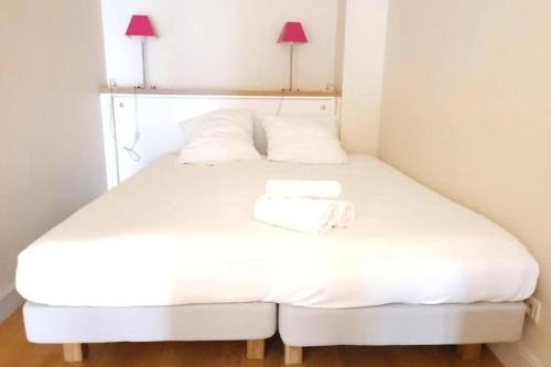 une chambre avec un lit blanc avec deux serviettes dessus dans l'établissement The Triplex - Cosy & Charming - Montorgueil, à Paris