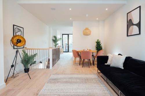 a living room with a black couch and a table at Luxurious & Modern London Apartment in Honor Oak in London