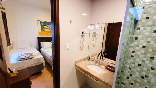 a bathroom with a sink and a shower and a bed at Pousada Casa da Sogra in Morro de São Paulo