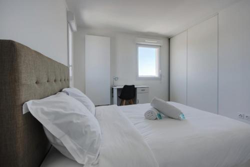 une chambre avec un lit blanc avec des oreillers blancs dans l'établissement T3 Duplex avec parking et balcon à Euromed, à Marseille