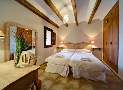 a bedroom with two beds and a table and a mirror at Apartamentos Turísticos Rincón de la Magdalena in Plasencia