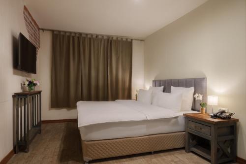 a bedroom with a large white bed and a table at Apricot Aghveran Resort in Agveran