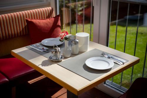 a table with plates and utensils on it next to a window at Villa Marienhof in Annenheim