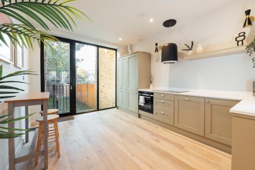 a kitchen with white cabinets and a large window at Luxurious & Modern London Apartment in Honor Oak in London