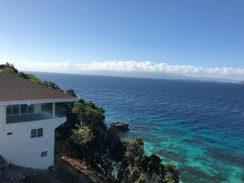 a house on a hill next to the ocean at Maha Villa - Sea View Island Retreat with private beach in Pinamihagan