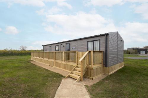 a tiny house with a wooden deck in a field at Host & Stay - Fieldview Lodge, Ashdown Retreat in Pickering