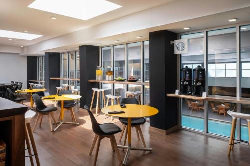 a restaurant with yellow tables and chairs and windows at Renaissance Minneapolis Bloomington Hotel in Bloomington