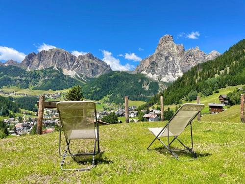 two chairs sitting on top of a field with mountains at Luxury Chalet Liosa - Ski in Ski out - Amazing view in Corvara in Badia