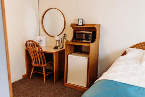 Habitación con escritorio, microondas y espejo. en Sportsmen Motel, en Jordan