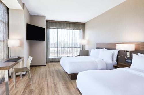a hotel room with two beds and a desk at AC Hotel by Marriott Huntsville Downtown in Huntsville