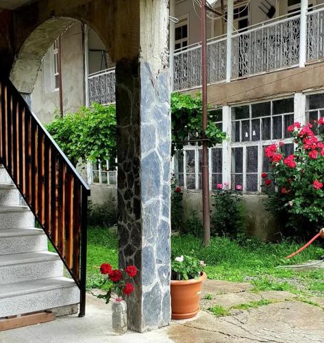 a building with a staircase and flowers in front of it at Guesthouse Bacha & Lia in Mestia