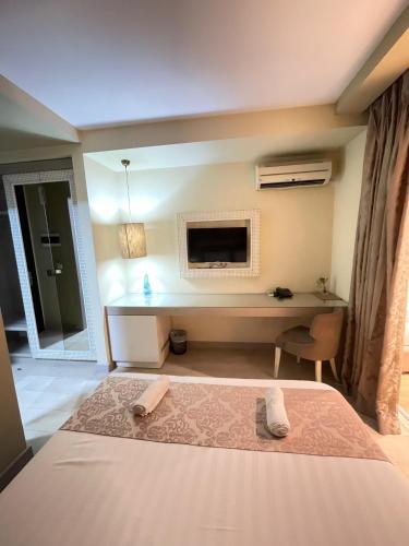 a bedroom with a bed and a desk with a television at New W Hotel in Tirana