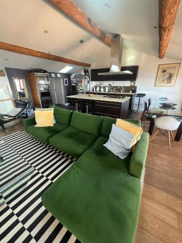 - un canapé vert dans le salon avec une cuisine dans l'établissement Somptueux Duplex Vue Mer Quartier-Haut, à Sète