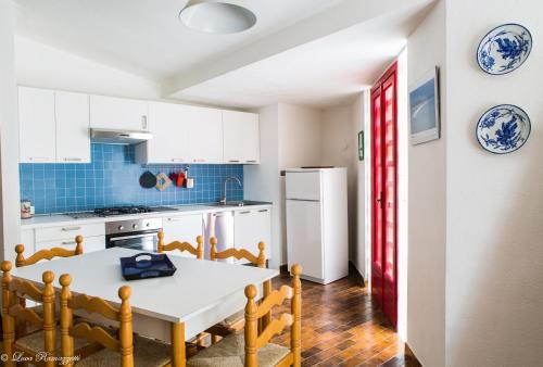 a kitchen with a white table and a white refrigerator at Le Case Bianche in Orosei
