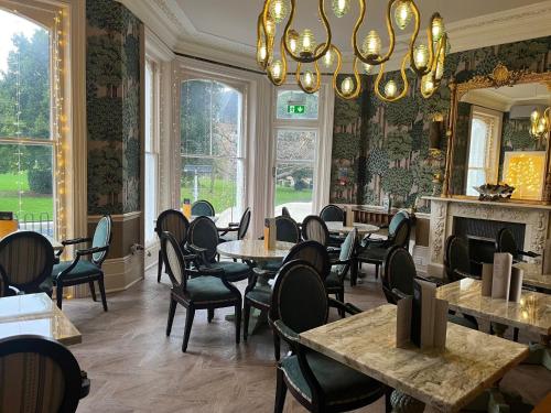 a restaurant with tables and chairs and a chandelier at voco The Clifton Folkestone by IHG in Folkestone