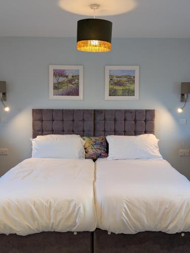 a bedroom with a large bed with white sheets at 4 Beechwood at Thoulstone Park in Westbury