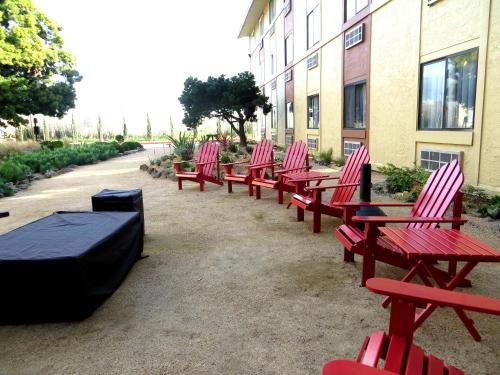 a row of red benches sitting next to a building at Hotel Focus SFO in South San Francisco