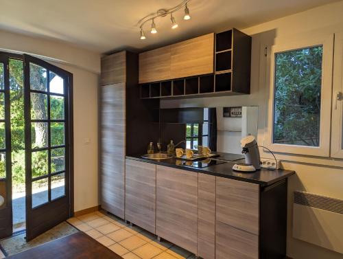 une cuisine avec des armoires en bois et un comptoir dans l'établissement Calme et verdure près de la mer, à Fréjus