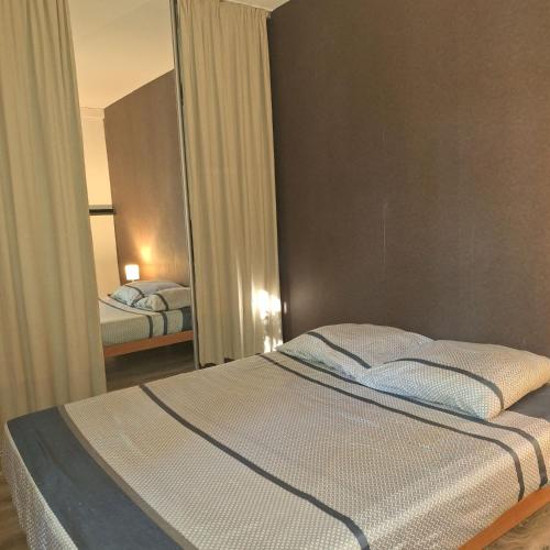 une chambre avec un lit et un grand miroir dans l'établissement Calme et verdure près de la mer, à Fréjus