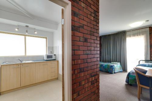 uma sala com uma parede de tijolos e uma cozinha e um quarto em Enfield Motel em Adelaide